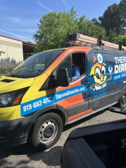 A Thermo Direct service van with company branding and cartoon mascot is parked outdoors; a person is visible in the driver's seat.